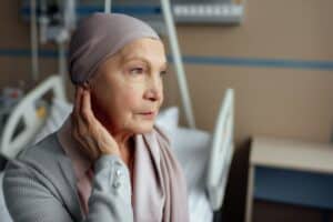 upset senior woman with cancer sitting on bed in hospital